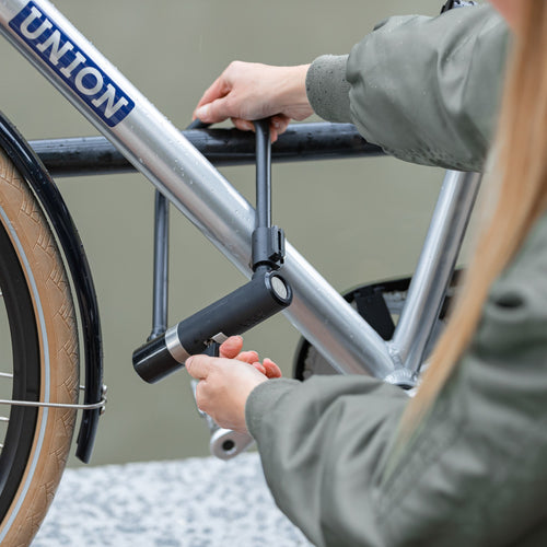 Cycliste qui verrouille son vélo avec un antivol U AXA Newton
