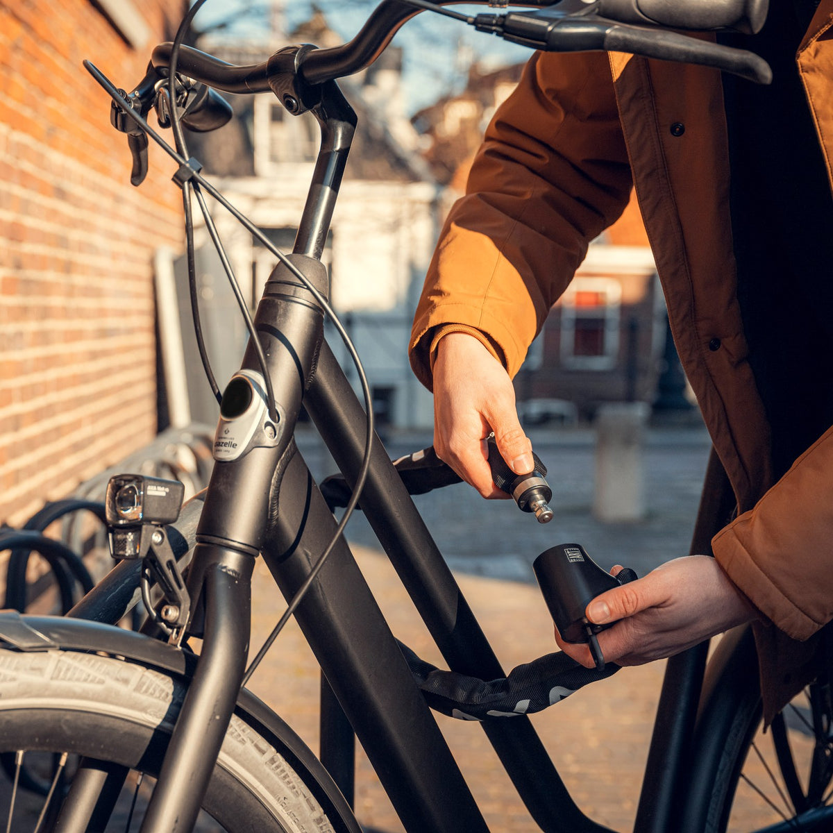 Cycliste qui verrouille la chaîne antivol AXA Absolute de son vélo