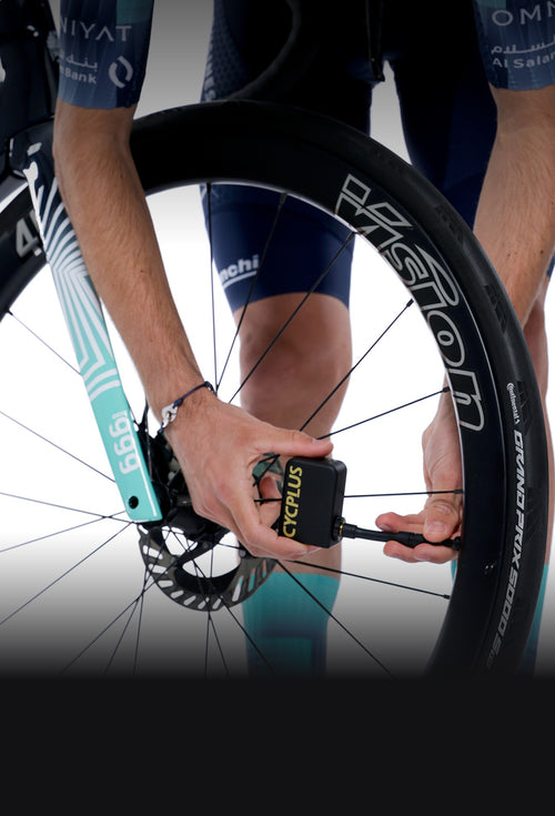 Mini pompe électrique vélo CYCPLUS AS2 Ultra utilisée par un mécanicien sur une roue