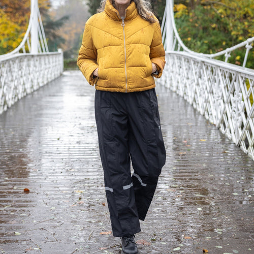 Femme en pantalon de pluie Hello Rain Budget noir sur un pont