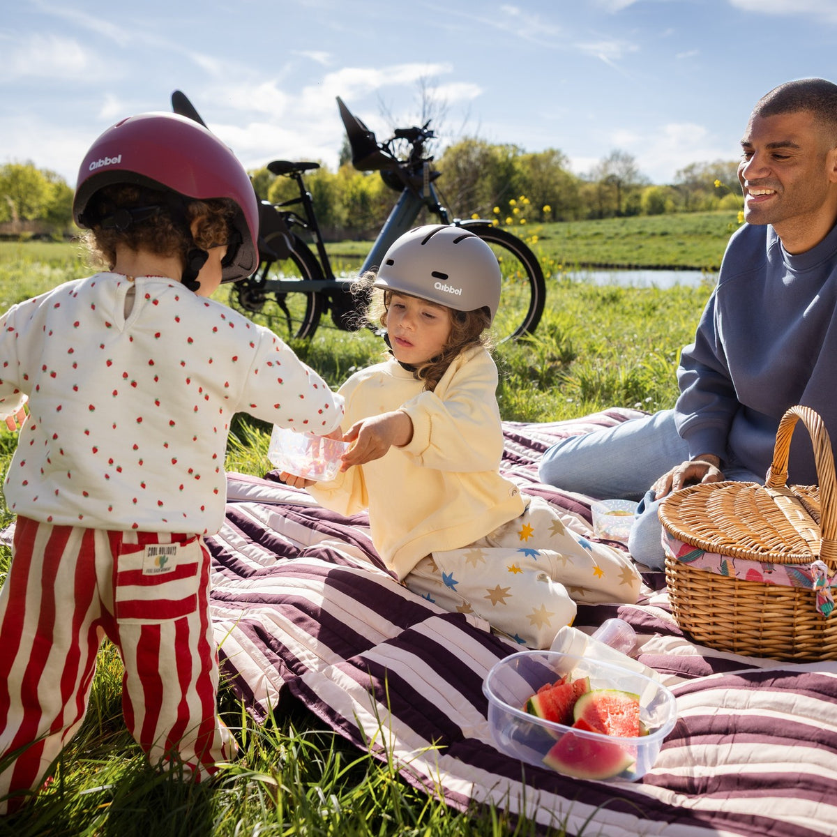 Famille en pause pique-nique avec ses vélos équipés de sièges enfant Qibbel