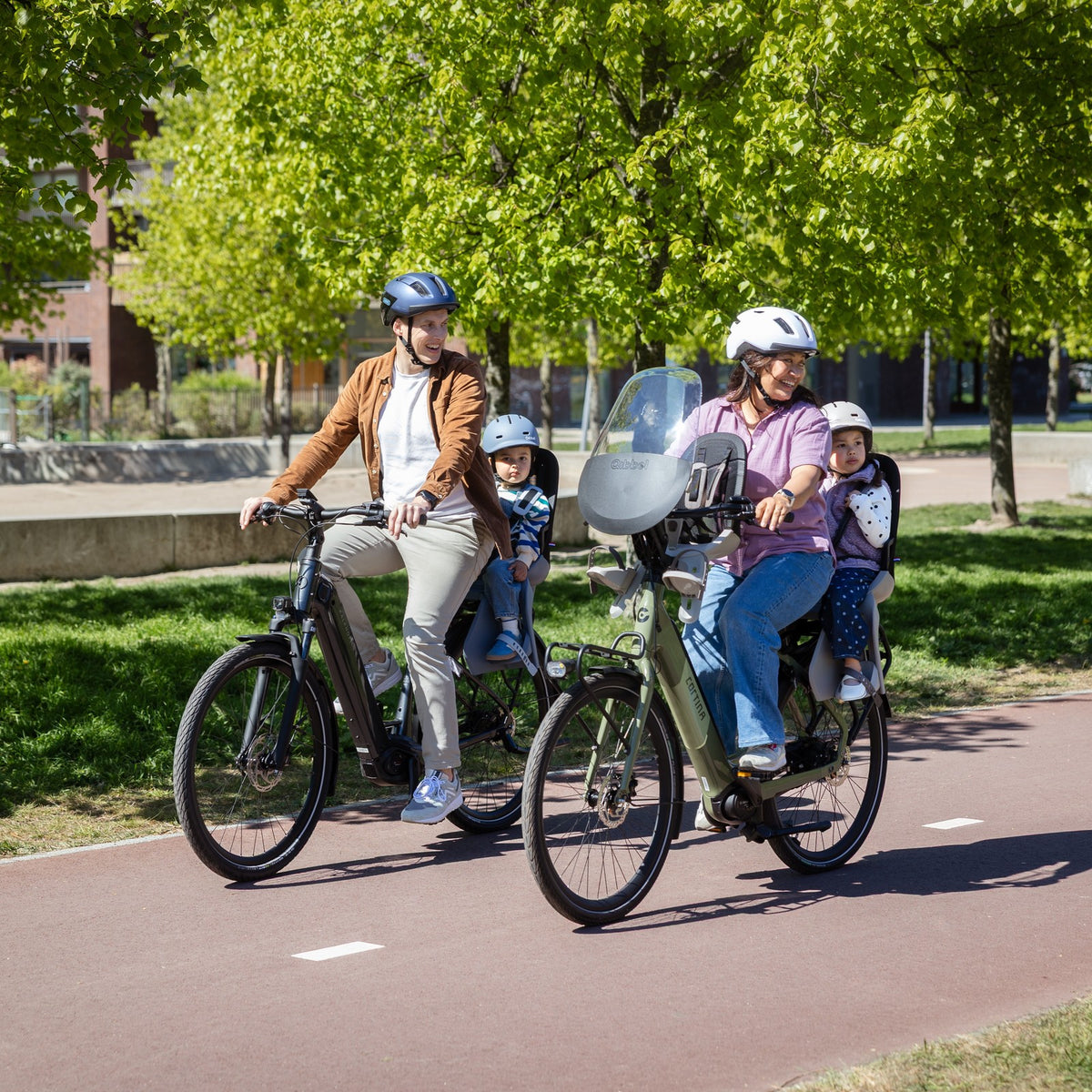 Parents à vélo avec enfants sur sièges vélo Qibbel sur piste cyclable