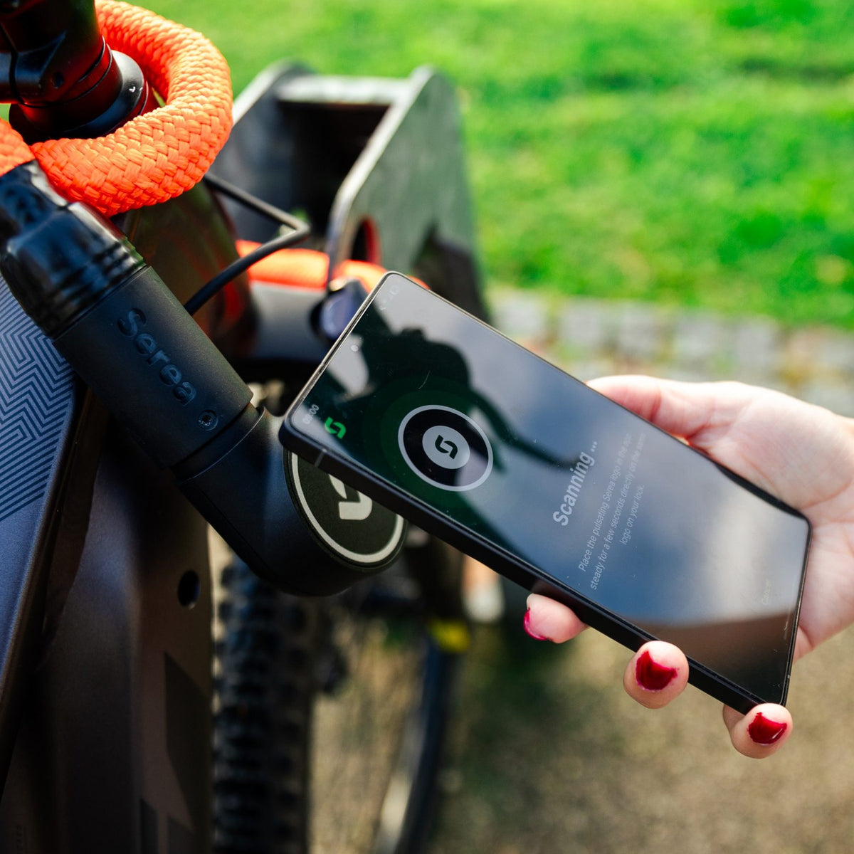 Smartphone posé sur l'antivol Serea Swift orange pour l'ouvrir sans clé