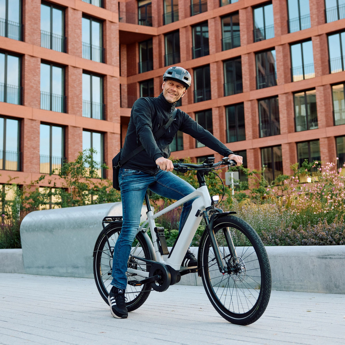 Cycliste à vélo électrique devant un immeuble en briques, campagne Trelock